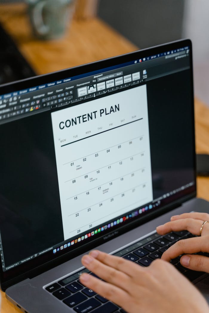 service-01 Close-up of hands typing on a laptop displaying a content plan document, ideal for business or marketing content.